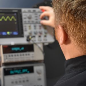 Technician working in front of an oscilloscope and integrating sphere test bench